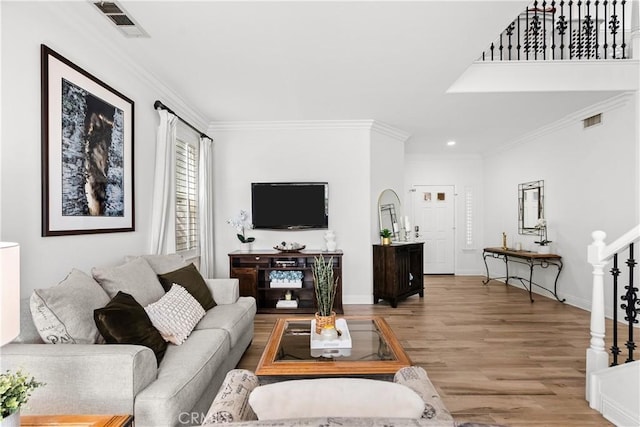 living area with light wood-style floors, stairs, visible vents, and ornamental molding