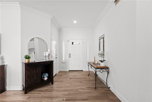 entrance foyer with ornamental molding, light wood-style flooring, and baseboards