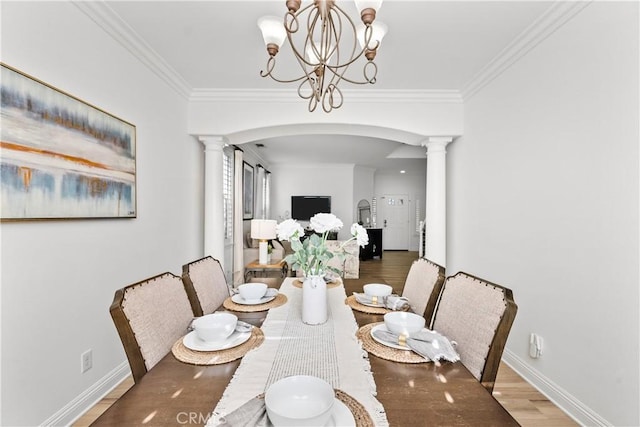 dining room with decorative columns, arched walkways, wood finished floors, and ornamental molding