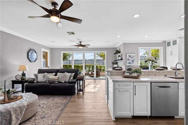 kitchen with visible vents, open floor plan, crown molding, stainless steel dishwasher, and a sink