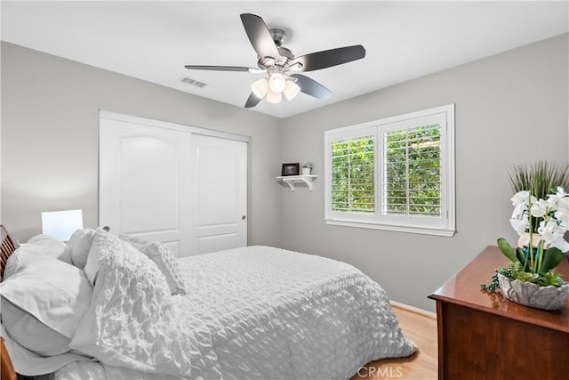 bedroom featuring light wood-style flooring, visible vents, ceiling fan, and a closet