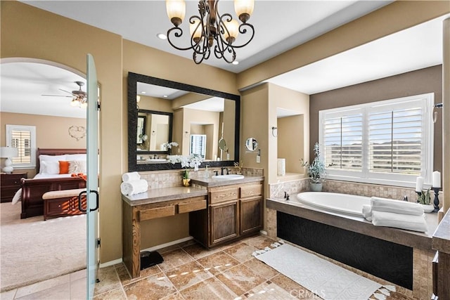 bathroom with ensuite bath, ceiling fan with notable chandelier, a bath, and vanity