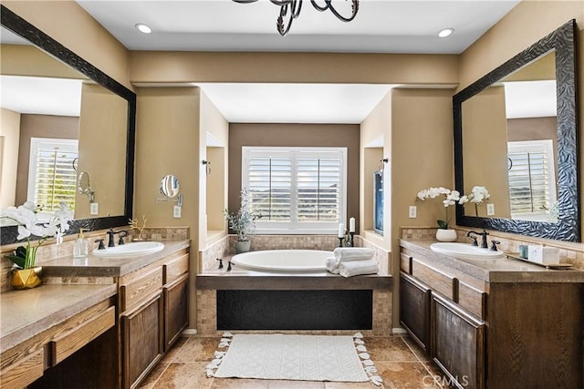 full bath featuring two vanities, a garden tub, and a sink