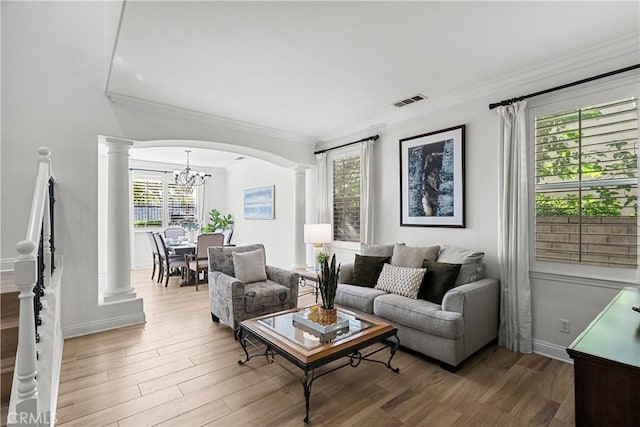 living area featuring decorative columns, visible vents, arched walkways, and wood finished floors