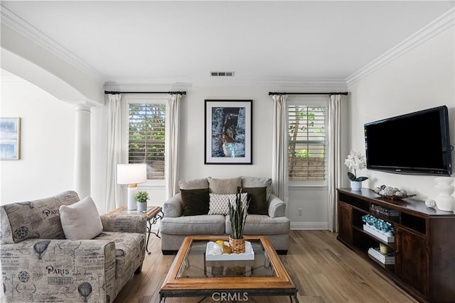 living area with decorative columns, visible vents, a wealth of natural light, and wood finished floors