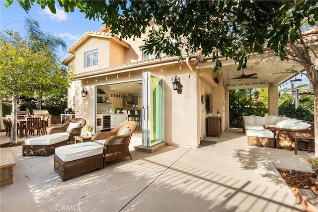 back of property with a ceiling fan, a patio area, an outdoor living space, and stucco siding