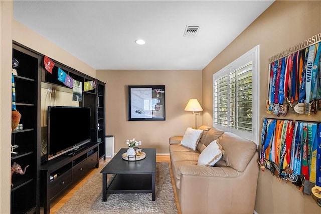 living room with recessed lighting, visible vents, and wood finished floors