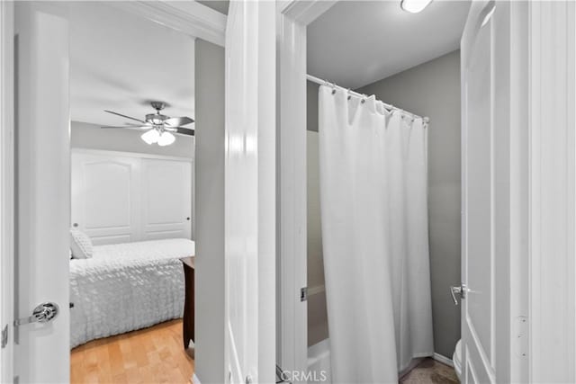 full bath with a shower with curtain, a ceiling fan, and wood finished floors