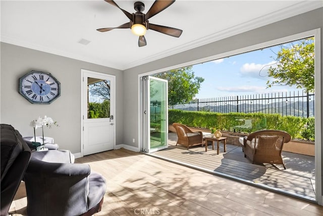 doorway to outside with ceiling fan, ornamental molding, wood finished floors, and baseboards