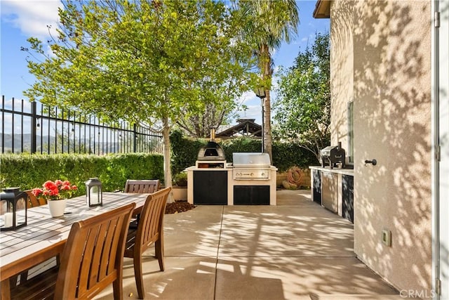 view of patio / terrace with an outdoor kitchen, outdoor dining space, area for grilling, and a fenced backyard