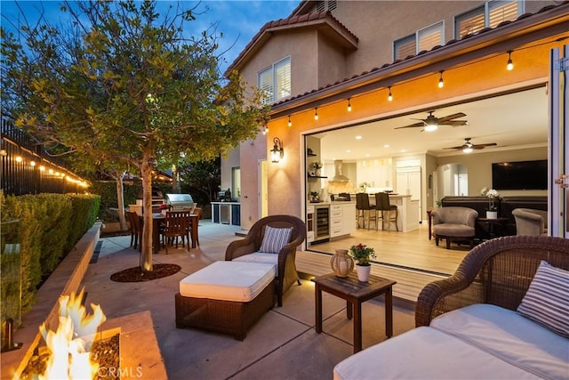 view of patio / terrace with exterior kitchen, outdoor dining space, beverage cooler, and an outdoor living space with a fire pit