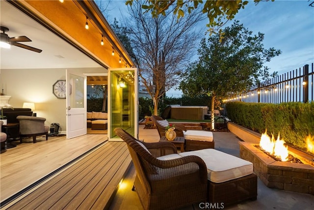 view of patio featuring an outdoor living space with a fire pit, a hot tub, a ceiling fan, fence, and a wooden deck