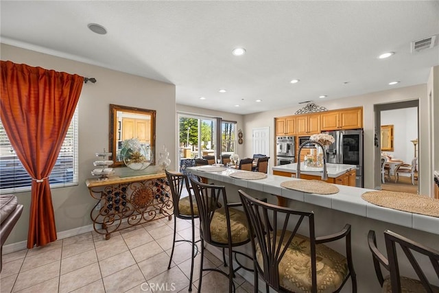 2503 N San Miguel Dr, Orange, CA 92867 - kitchen with appliances with stainless steel finishes, a center island, a kitchen bar, light tile patterned flooring, and recessed lighting