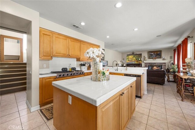 2503 N San Miguel Dr, Orange, CA 92867 - kitchen with stainless steel appliances, light tile patterned floors, tile counters, a peninsula, and a kitchen island