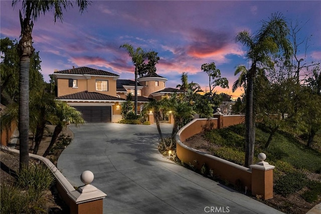 view of front of home featuring a garage, a tiled roof, concrete driveway, and stucco siding