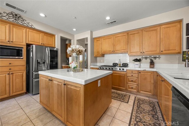 2503 N San Miguel Dr, Orange, CA 92867 - kitchen featuring appliances with stainless steel finishes, tile countertops, light tile patterned flooring, a kitchen island, and decorative backsplash