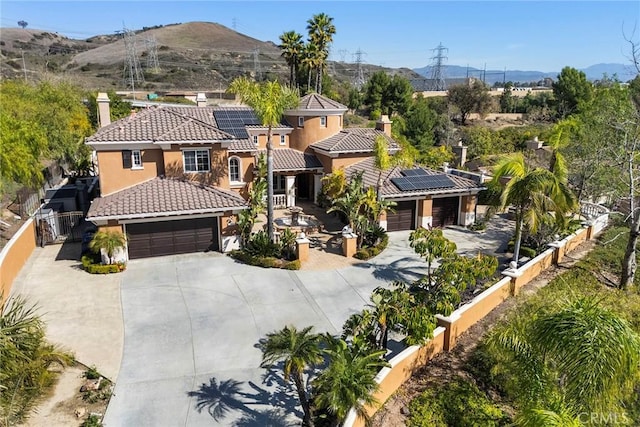 2503 N San Miguel Dr, Orange, CA 92867 - mediterranean / spanish-style home featuring stucco siding, a tile roof, concrete driveway, a chimney, and roof mounted solar panels