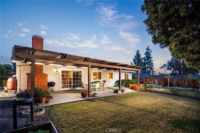 back house at dusk featuring a yard, a pergola, and a patio area