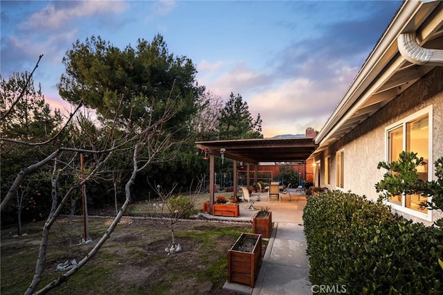 yard at dusk featuring a patio area