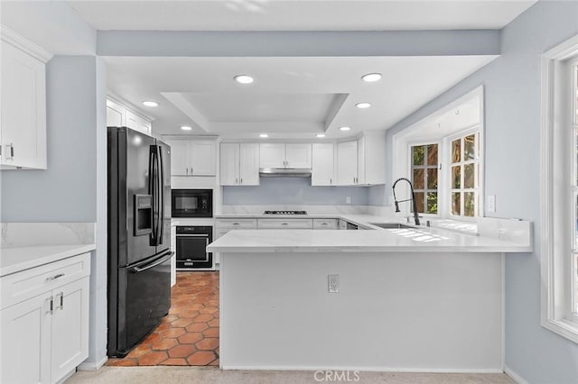 kitchen featuring white cabinetry, kitchen peninsula, black appliances, a tray ceiling, and sink