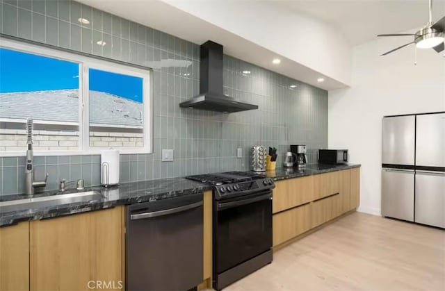 kitchen with sink, dishwasher, range with gas stovetop, wall chimney exhaust hood, and stainless steel fridge