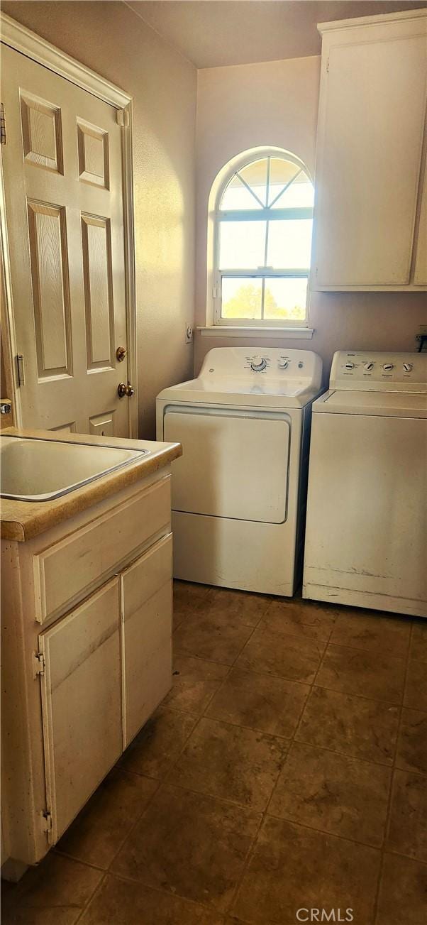 washroom with dark tile patterned flooring, independent washer and dryer, a sink, and cabinet space