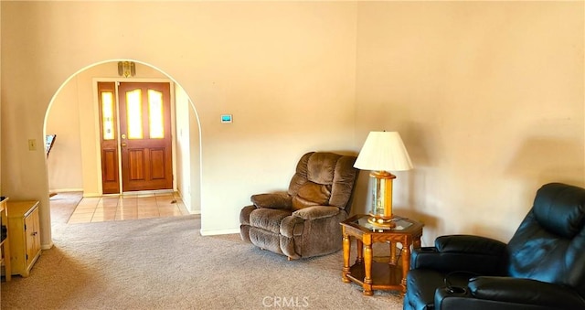 living area with light colored carpet, arched walkways, and baseboards