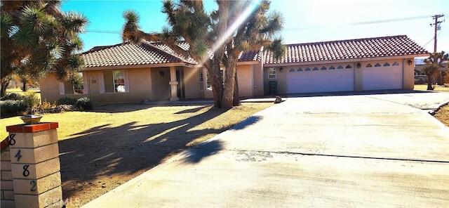 mediterranean / spanish-style home featuring a tile roof, driveway, an attached garage, and stucco siding