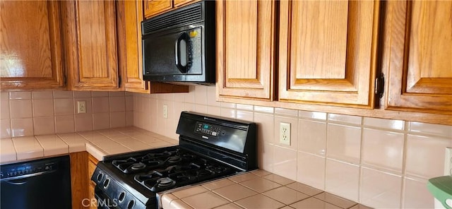 kitchen with brown cabinetry, tile counters, tasteful backsplash, and black appliances