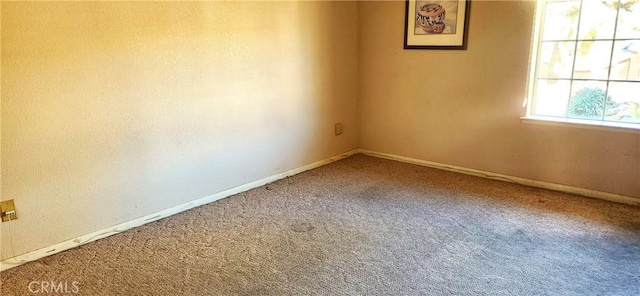 empty room featuring carpet flooring and baseboards