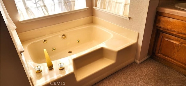 bathroom featuring a tub with jets and carpet floors