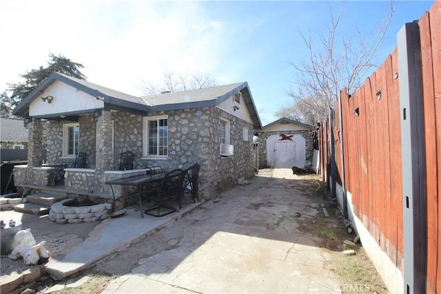 back of house with stone siding, a patio area, and fence