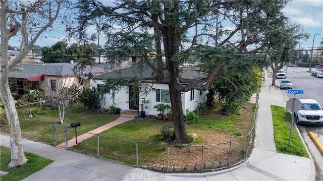 view of front facade featuring a fenced front yard, a front yard, and stucco siding