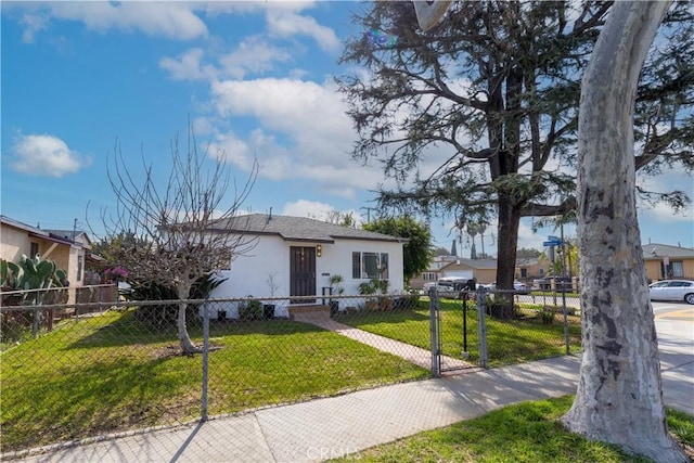 view of front facade featuring a fenced front yard, a front lawn, and stucco siding