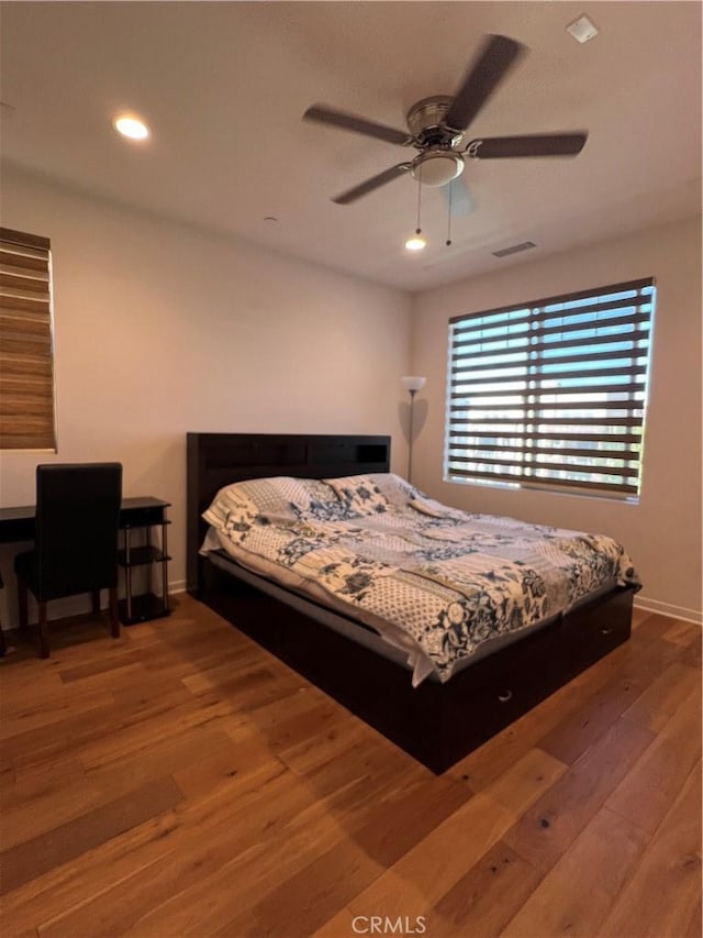 bedroom featuring baseboards, wood finished floors, visible vents, and recessed lighting