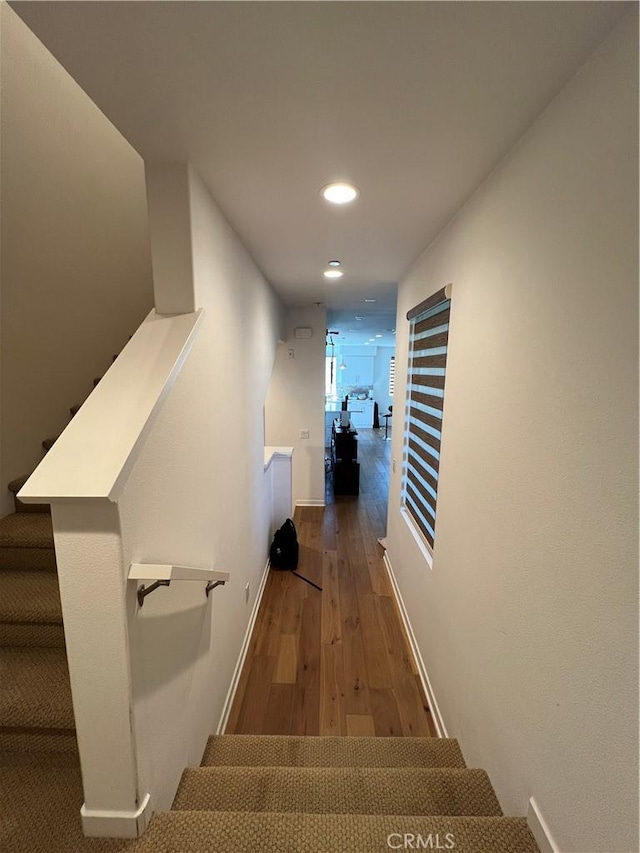 corridor with stairs, recessed lighting, wood finished floors, and baseboards