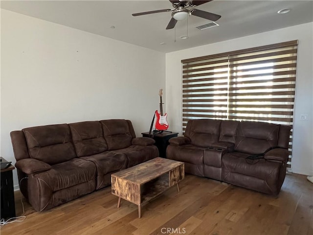 living room with visible vents, ceiling fan, and hardwood / wood-style flooring