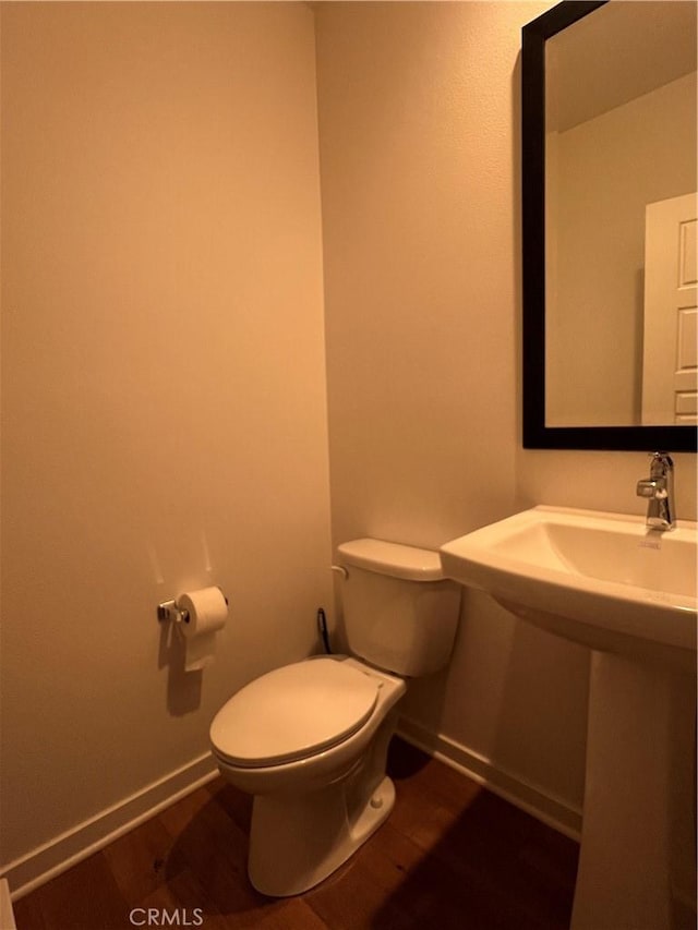 bathroom featuring baseboards, toilet, and wood finished floors