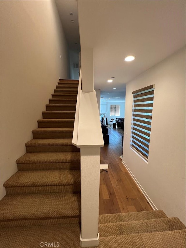 stairs with wood finished floors and recessed lighting