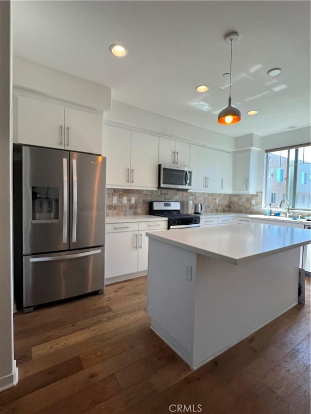 kitchen with appliances with stainless steel finishes, white cabinetry, dark wood finished floors, and decorative backsplash