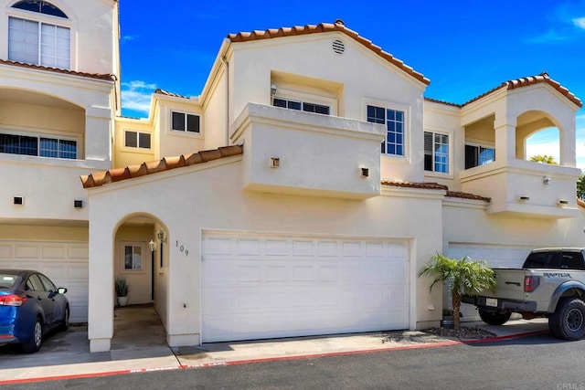 mediterranean / spanish house featuring stucco siding, an attached garage, and a tile roof