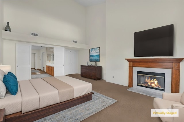 bedroom with carpet, ensuite bath, and a towering ceiling