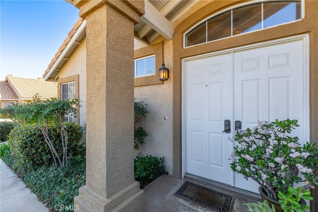 entrance to property featuring stucco siding and a tile roof