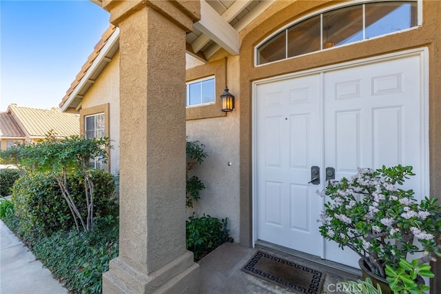 entrance to property with a tile roof and stucco siding