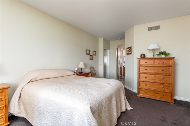 bedroom featuring arched walkways, baseboards, visible vents, and dark carpet