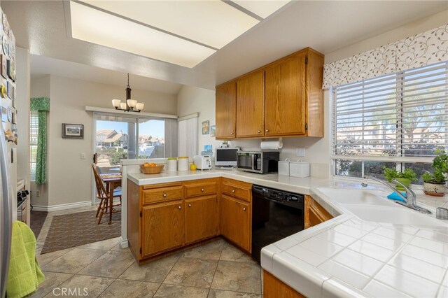 kitchen with a notable chandelier, stainless steel microwave, black dishwasher, a peninsula, and tile counters