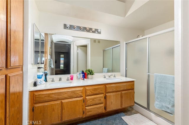 full bathroom with a sink, a shower stall, and double vanity