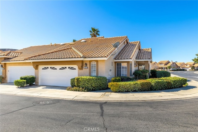 view of front of home with a tile roof, stucco siding, driveway, and an attached garage