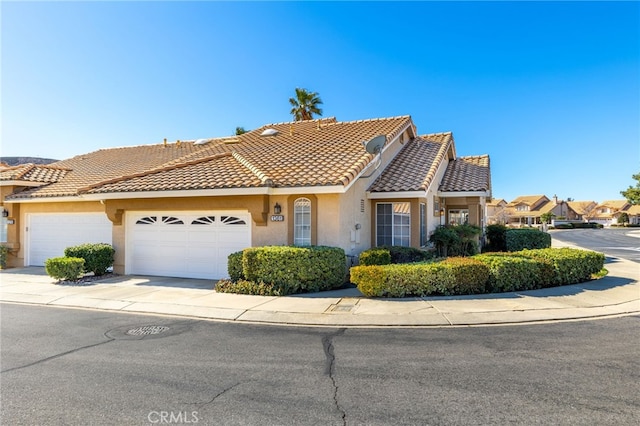 view of front of home featuring an attached garage, a tile roof, driveway, and stucco siding