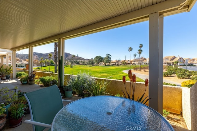 sunroom featuring a residential view, outdoor dining space, and a mountain view